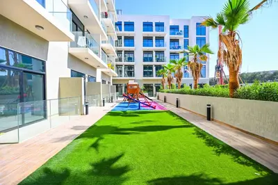 a lawn in the middle of a building with a playground at Modern Studio with Balcony and Pool Access - Holiday Boulevard in Dubai