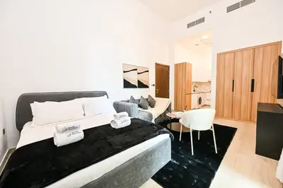 a bedroom with a large bed and a living room at Modern Studio with Balcony and Pool Access - Holiday Boulevard in Dubai