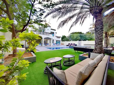 a patio with a couch and tables and a palm tree at Signature 7-bedroom Villa Marina in Dubai