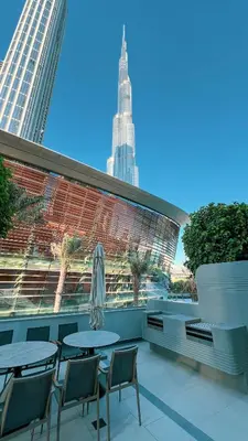a patio with tables and chairs and a view of a building at Grande Signature by Emaar! Amazing Pool, Gym and Location! in Dubai