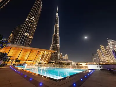 a large swimming pool in a city at night at Grande Signature by Emaar! Amazing Pool, Gym and Location! in Dubai