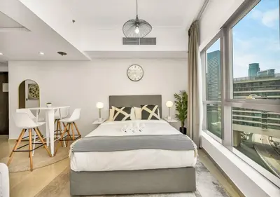 a bedroom with a bed and a table and a clock at Bay Central Modern Studio in Dubai