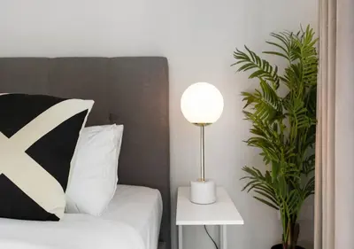 a bedroom with a bed with a lamp and a plant at Bay Central Modern Studio in Dubai