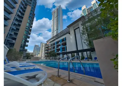 a swimming pool with lounge chairs next to some buildings at Luxe Vista - Top Location Dubai Marina 1BR - Metro and Beach Access in Dubai
