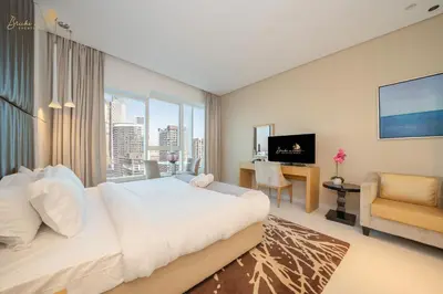 a bedroom with a large bed and a desk and a television at Cozy Canal View Studio in Dubai