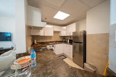a kitchen with white cabinets and a stainless steel refrigerator at Homes & Beyond l 2BR in the Heart of Dubai Marina in Dubai
