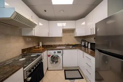 a kitchen with white cabinets and a washer and dryer at Homes & Beyond l 2BR in the Heart of Dubai Marina in Dubai