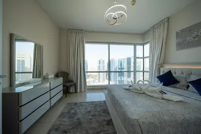 a bedroom with a bed and a large window at Homes & Beyond l 2BR in the Heart of Dubai Marina in Dubai