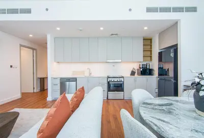 a kitchen and dining room with white cabinets and a table at Brand New Stylish 2 BR with Balcony in Dubai