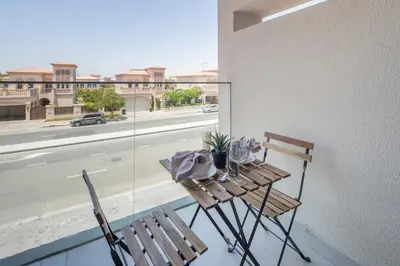 a table and chairs on a balcony with a view of a street at Frank Porter - Bali Residences in Dubai