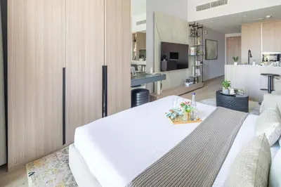 a living room with a white table and a kitchen at Frank Porter - Bali Residences in Dubai