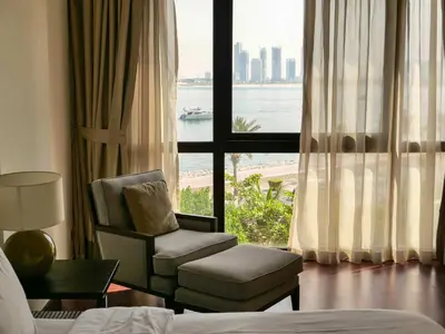a hotel room with a chair and a large window at Oceanfront 2BR Apartment with Perfect Views in Dubai
