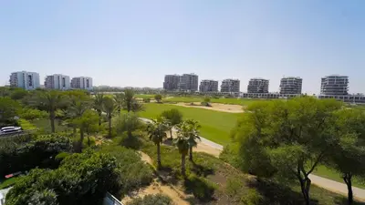 a view of a park with palm trees and buildings at AWS Holiday Homes - Charming stay near Golf Course in Dubai