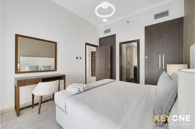 a bedroom with a white bed and a desk and mirror at Cayan Escape Lavish 1BR with Sea View in Dubai