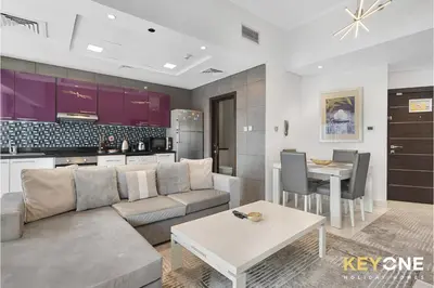 a living room with a couch and a table and a kitchen at Cayan Escape Lavish 1BR with Sea View in Dubai
