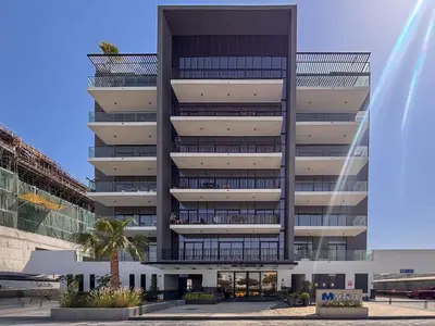 a tall building with a palm tree in front of it at Frank Porter - MYKA Residence in Dubai