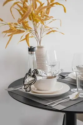 a table with a plate and a vase with a plant at Frank Porter - MYKA Residence in Dubai