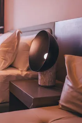 a black lamp on a table next to a bed at Voyage Studio In Mag City in Dubai