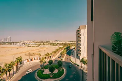 arial view of a street with palm trees and a beach at Voyage Studio In Mag City in Dubai