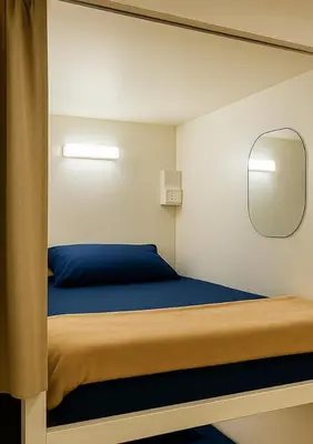 a small bedroom with a bed with a mirror at Devine Homes JBR Hostel in Dubai