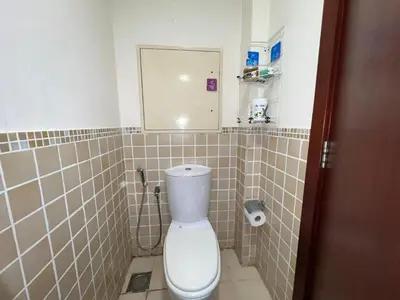 a bathroom with a toilet with a mirror and tiled walls at Devine Homes JBR Hostel in Dubai