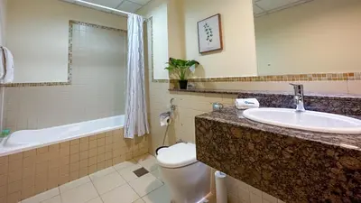 a bathroom with a sink and a toilet and a tub at Devine Homes JBR Hostel in Dubai