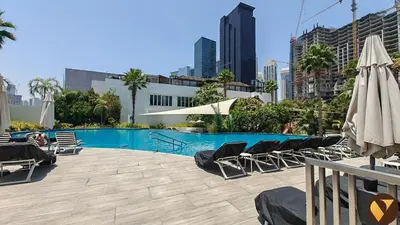 a swimming pool with chairs and umbrellas in a city at Vogue JLT Banyan Tree Residences Hillside, near Marina and JBR, Two Bedroom Apartment with Balcony and City View, Access to all Amenities in Dubai