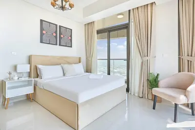 a white bedroom with a bed and a chair at Aykon City 2BR Luxury Stay Close to Downtown in Dubai
