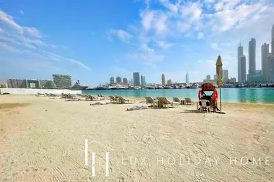 a beach with chairs and a city in the background at LUX The Marina Vista Beachfront Suite 5 in Dubai