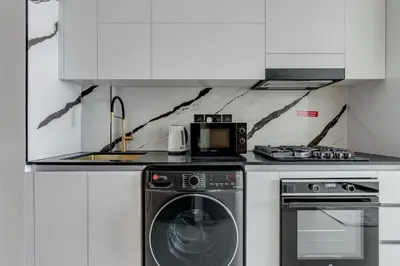 a kitchen with a washing machine and a microwave at Luxury Studio with Jacuzzi & Canal Views in Dubai