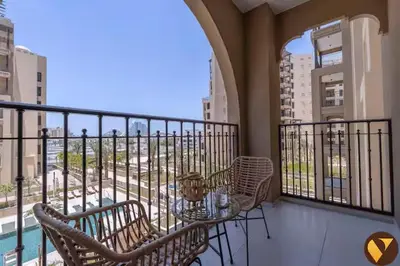 a balcony with a table and chairs on a balcony at Vogue Madinat Jumeirah Living Jadeel near Burj AlArab, One-Bedroom Apartment with Large Balcony and Pool View, Access to All Amenities in Dubai