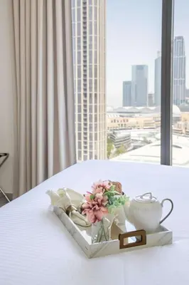 a tray with a tea pot and flowers on a bed at Frank Porter - Forte Tower 1 in Dubai