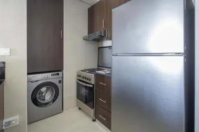 a kitchen with a refrigerator and a washing machine at Frank Porter - Kappa Acca 3 in Dubai