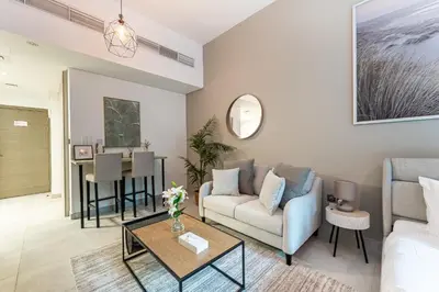 a living room with a couch and a table at HAVN - Studio in La Riviera Azure JVC, Pool View in Dubai