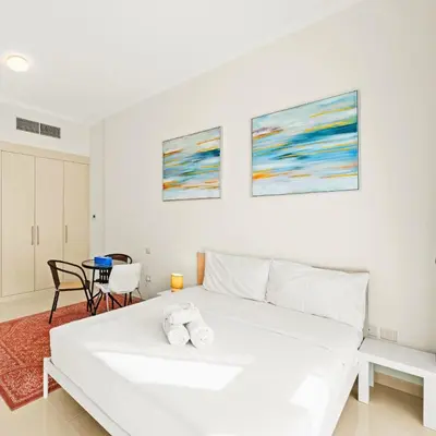 a bedroom with a white bed with two towels on it at Damac Hills Carson A Monthly Stay - Pay 28, Stay 30 in Dubai