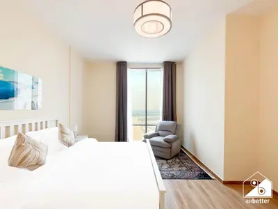 a bedroom with a bed and a chair and a window at Business Bay 2BR in Amna Tower & Canal Views in Dubai