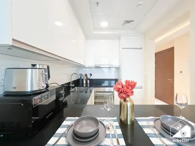 a kitchen with a table with glasses and a vase with flowers at Business Bay 2BR in Amna Tower & Canal Views in Dubai