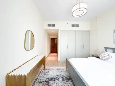a white bedroom with two beds and a mirror at Business Bay 2BR in Amna Tower & Canal Views in Dubai