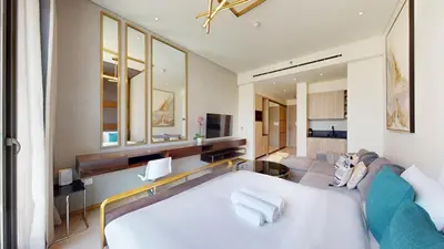 a bedroom with a large white bed and a couch at Signature Livings - Bright Studio in JVC in Dubai