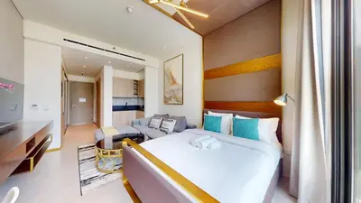 a bedroom with a large bed and a living room at Signature Livings - Bright Studio in JVC in Dubai