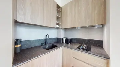 a kitchen with wooden cabinets and a sink at Signature Livings - Bright Studio in JVC in Dubai
