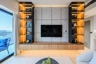 a living room with a flat screen tv on a wall at Binghatti Emerald, Jumeirah Village Circle in Dubai