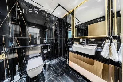 a bathroom with a toilet and a sink and a mirror at Binghatti Emerald, Jumeirah Village Circle in Dubai
