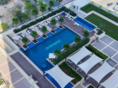 an overhead view of a pool with palm trees and chairs at Stylish 2BR Retreat in JVC in Dubai
