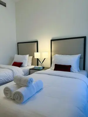 two beds in a hotel room with towels on them at Stylish 2BR Retreat in JVC in Dubai