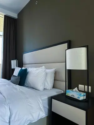 a bedroom with a white bed with a nightstand and a lamp at Stylish 2BR Retreat in JVC in Dubai