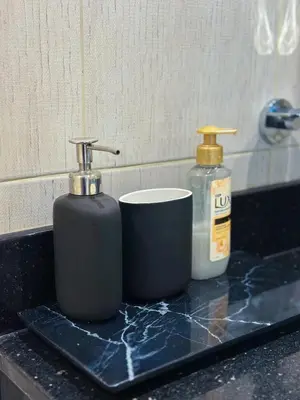 two bottles of soap and a cup on a bathroom counter at Stylish 2BR Retreat in JVC in Dubai