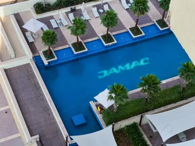 an overhead view of a swimming pool with palm trees at Stylish 2BR Retreat in JVC in Dubai