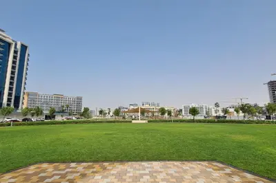 a large grass field with buildings in the background at Burj View - Luxury Studio - Near Dubai Miracle & Butterfly Garden- Arjan, Dubailand in Dubai
