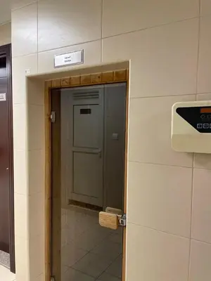 a door in a bathroom with a sign on the wall at Sport City with gym, pool, sauna in Dubai